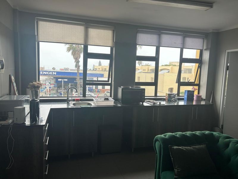 Open-plan kitchen area featuring granite countertops, built-in cabinetry, and large windows with roller blinds, providing functional workspace within the living area.