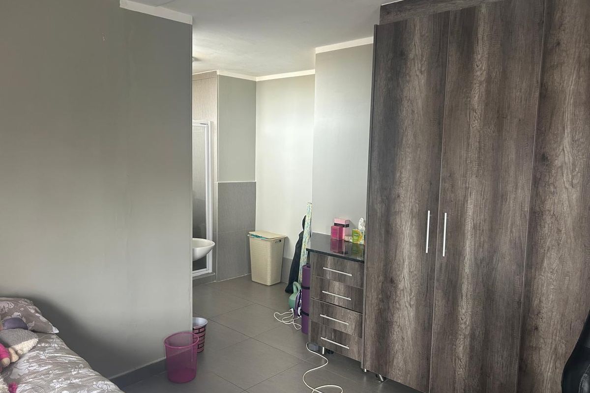 A bedroom featuring tiled flooring and a large built-in wardrobe, with direct access to an en-suite bathroom.