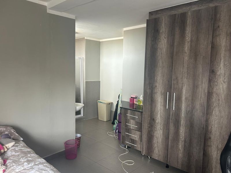 A bedroom featuring tiled flooring and a large built-in wardrobe, with direct access to an en-suite bathroom.