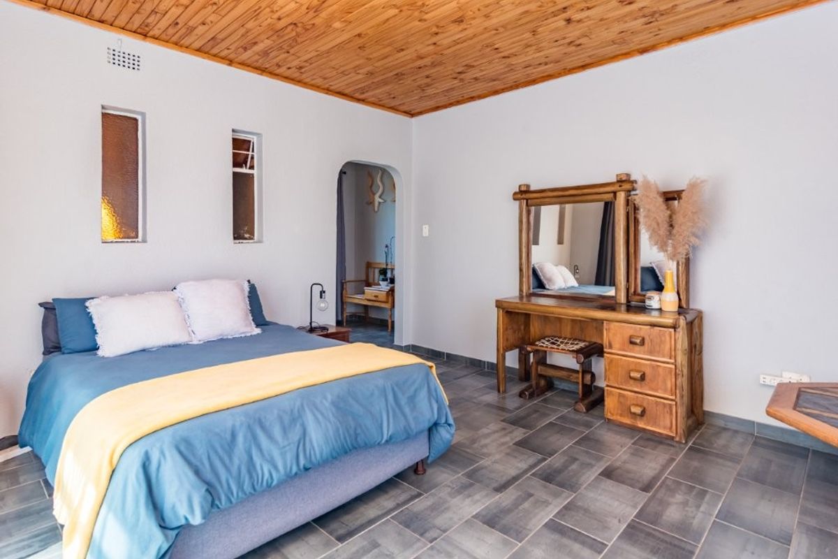 A spacious bedroom featuring a warm timber ceiling, tiled flooring, and an arched doorway leading to an adjoining space.