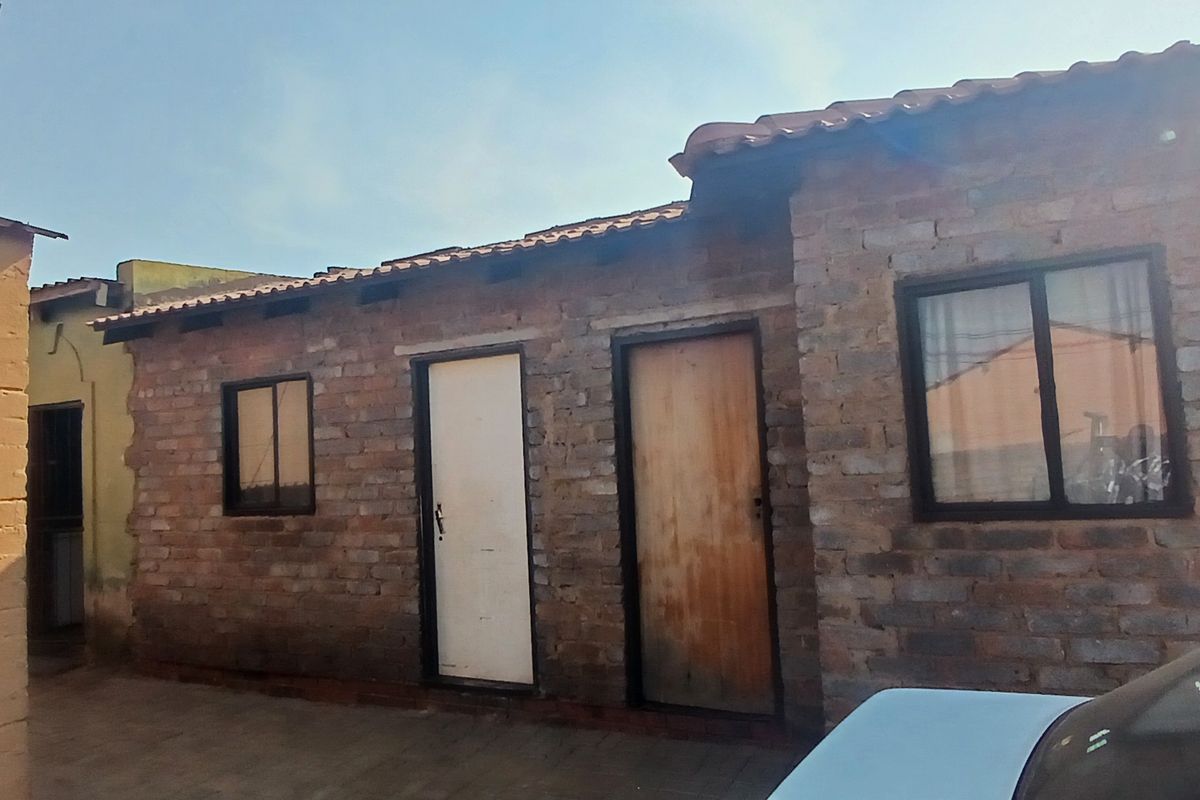 Exterior view of a residential building featuring exposed brick walls, tiled roofing, and multiple entry points with sliding windows.