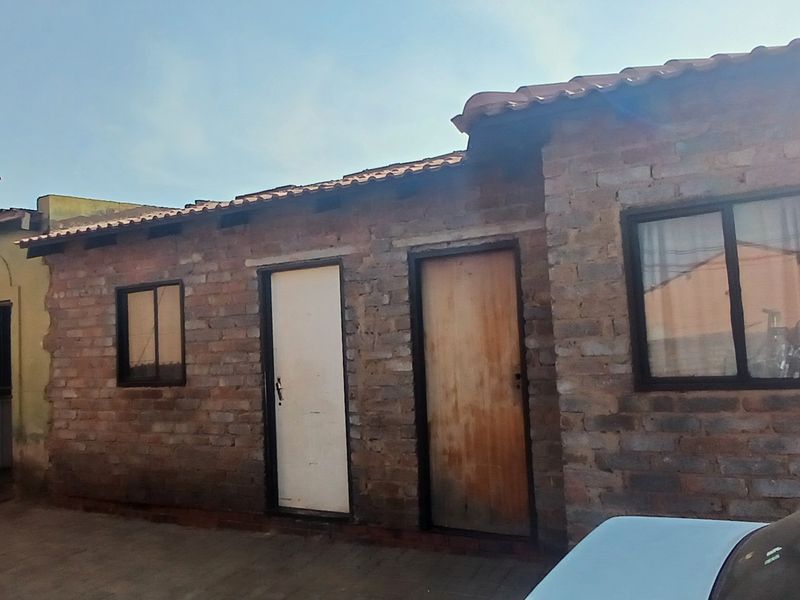 Exterior view of a residential building featuring exposed brick walls, tiled roofing, and multiple entry points with sliding windows.