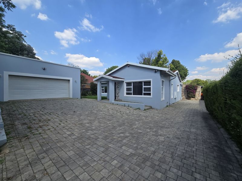 Front exterior view of a single-story house featuring a paved driveway, detached garage, and a covered entrance porch with well-maintained exterior walls.