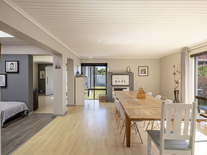 Spacious open-plan dining area featuring light laminate flooring, a tongue and groove ceiling, a built-in fireplace, and large sliding doors leading to the garden.