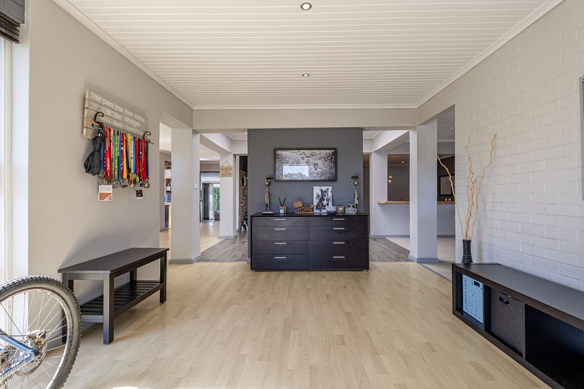 Spacious living area featuring light laminate flooring, a painted brick feature wall, and a clean tongue and groove ceiling with recessed lighting.