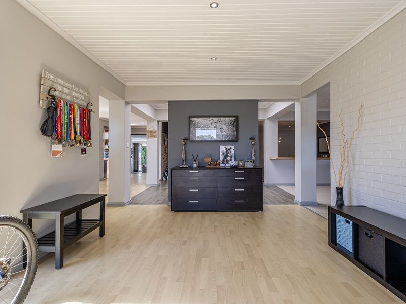 Spacious living area featuring light laminate flooring, a painted brick feature wall, and a clean tongue and groove ceiling with recessed lighting.