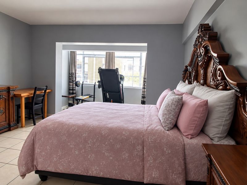 Spacious bedroom featuring tiled flooring and a recessed window area, providing a comfortable and functional living space.