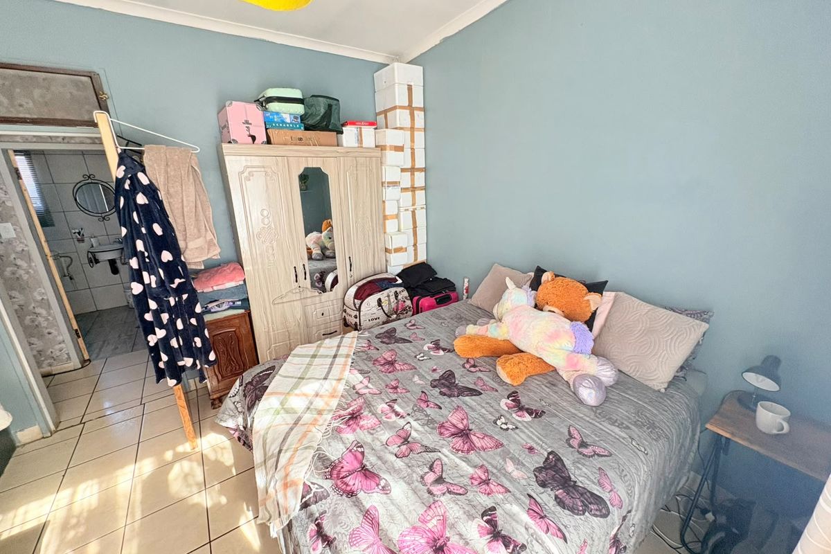 A bedroom featuring tiled flooring and coved ceilings, with an adjacent bathroom visible through the doorway.