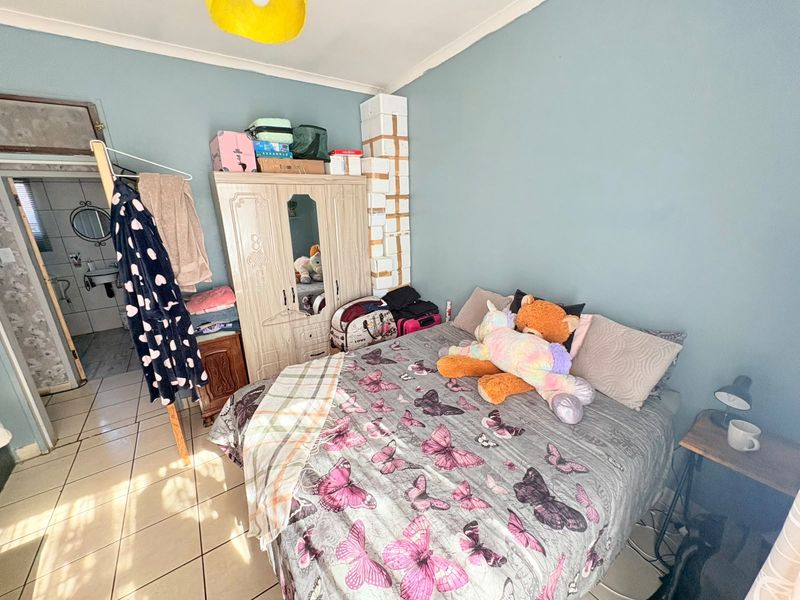 A bedroom featuring tiled flooring and coved ceilings, with an adjacent bathroom visible through the doorway.