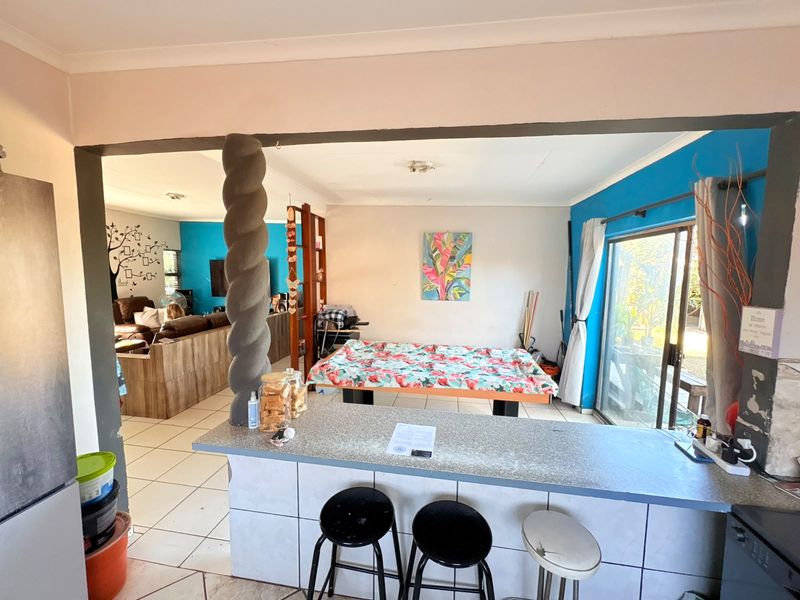 Open plan living area featuring a breakfast bar, tiled flooring, and sliding glass doors leading to the exterior.