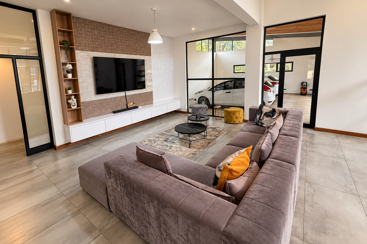 Modern living room featuring large-format tiled floors, custom built-in media cabinetry with integrated shelving, and stylish black-framed glass partitions overlooking the garage area.