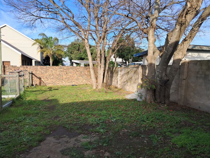 A private rear garden area featuring mature trees and a combination of brick and concrete boundary walls, offering potential for landscaping improvements.