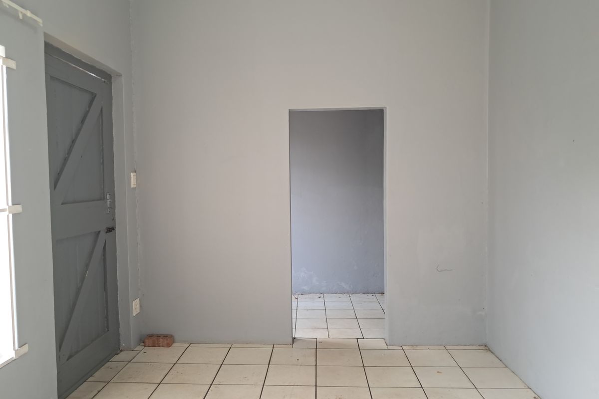 An empty living area featuring tiled flooring and a neutral grey paint scheme, providing a blank canvas for interior design.