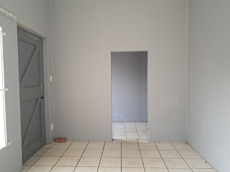 An empty living area featuring tiled flooring and a neutral grey paint scheme, providing a blank canvas for interior design.