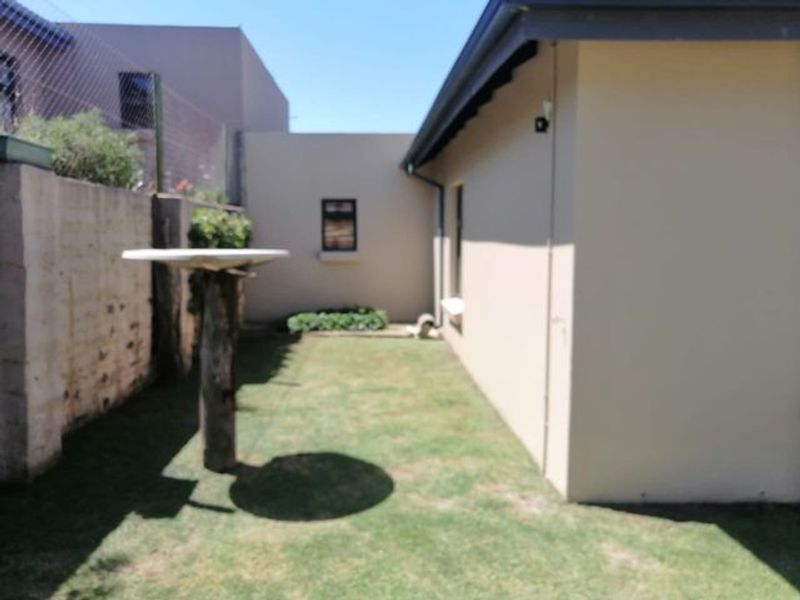 A side garden area featuring a lawn, boundary wall, and exterior building facade.