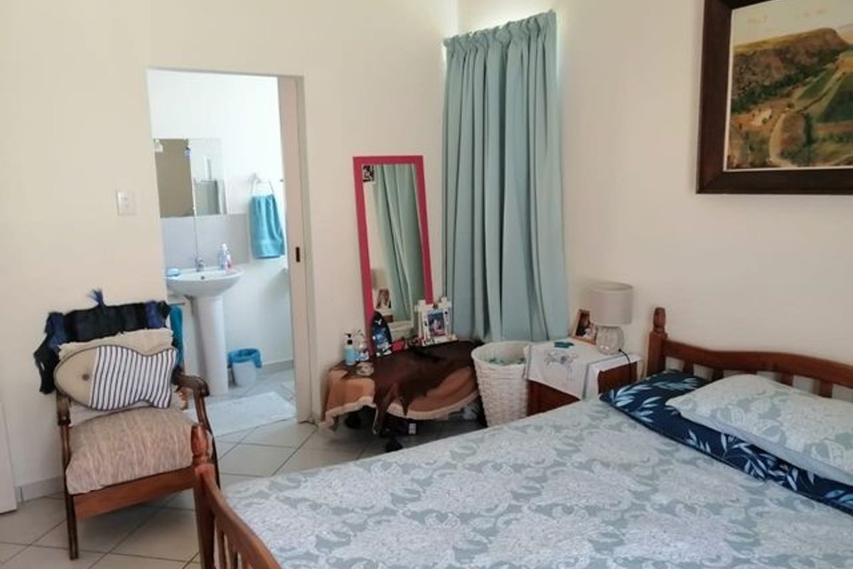 A bedroom featuring tiled flooring and an en-suite bathroom with a pedestal basin, offering a functional and comfortable living space.