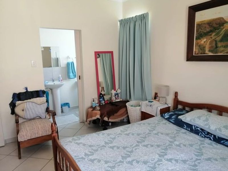A bedroom featuring tiled flooring and an en-suite bathroom with a pedestal basin, offering a functional and comfortable living space.