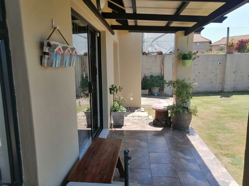 A covered patio area featuring tiled flooring and direct access to the garden through a sliding glass door.