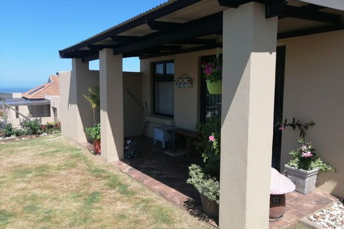 A covered outdoor patio area featuring tiled flooring and concrete support pillars, providing a pleasant space for outdoor relaxation.