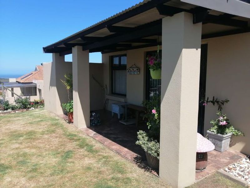 A covered outdoor patio area featuring tiled flooring and concrete support pillars, providing a pleasant space for outdoor relaxation.