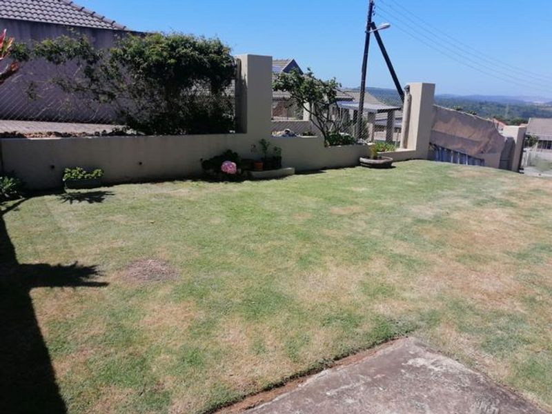 A private garden area featuring a lawn, boundary wall, and concrete paving, offering potential for landscaping improvements.