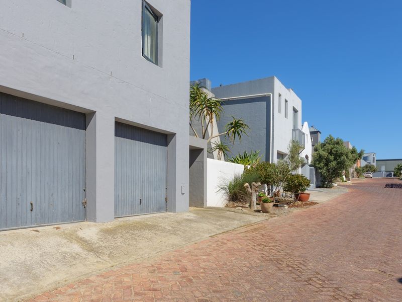 Street view of a townhouse complex featuring double garages, paved driveways, and well-maintained exterior facades.