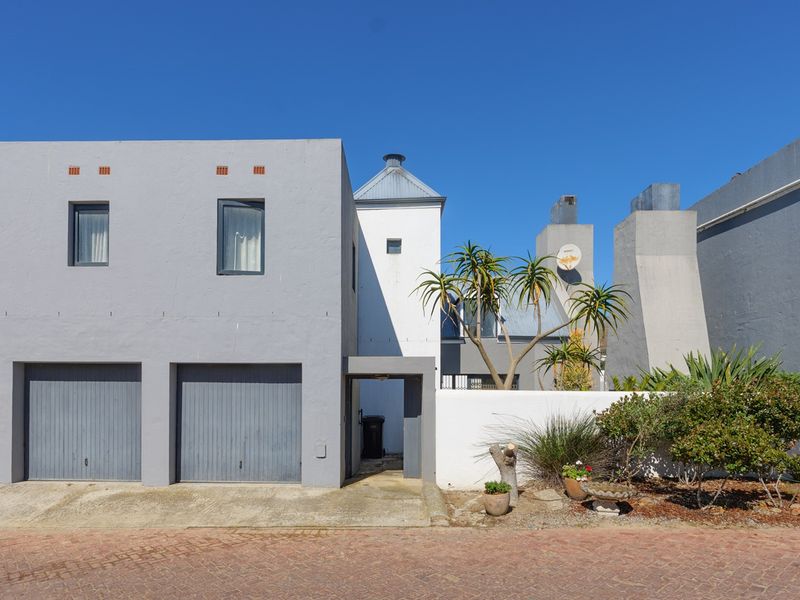 Front elevation of a modern townhouse featuring a double garage, concrete driveway, and clean architectural lines with a paved street approach.