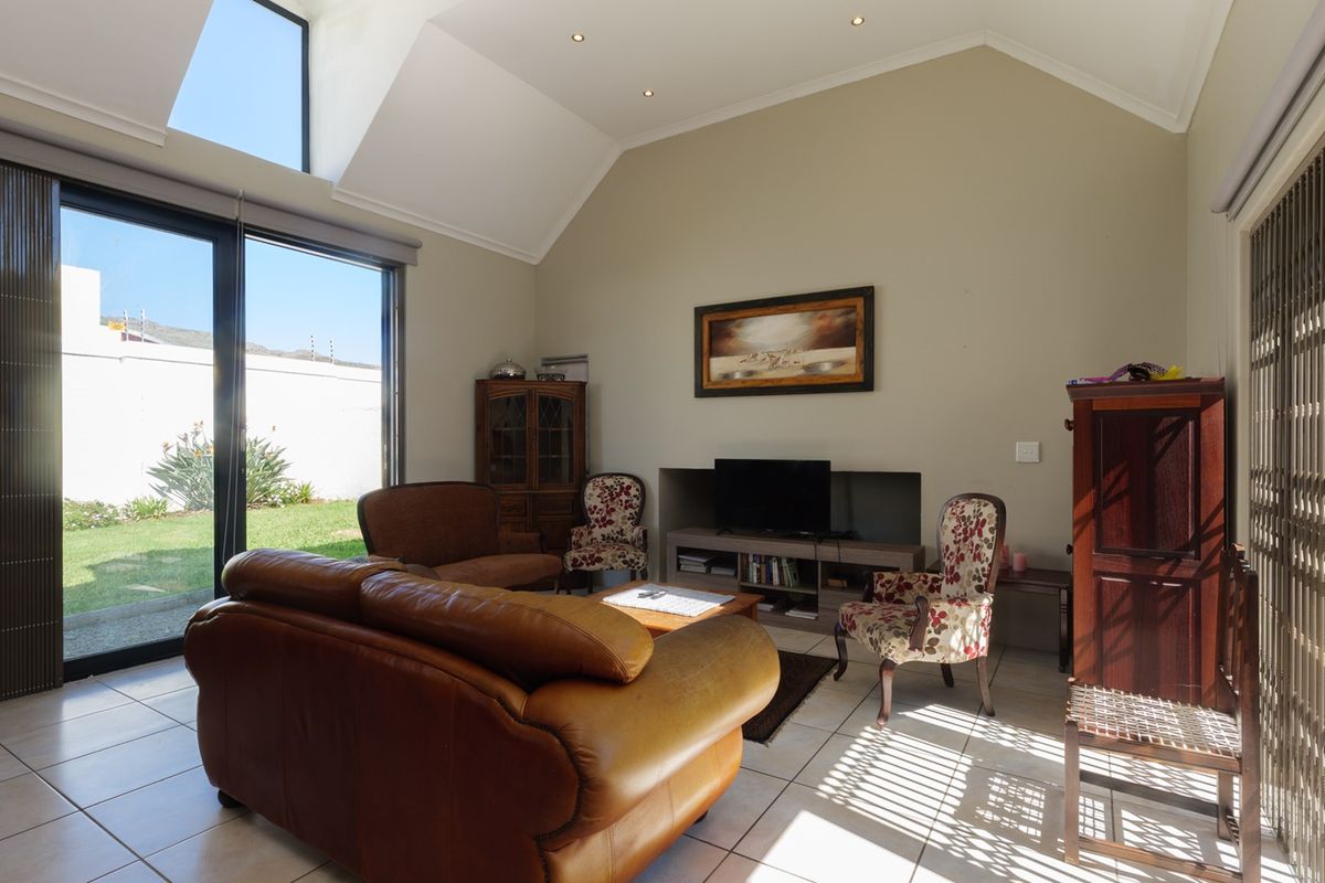 Spacious living room featuring a high vaulted ceiling, large skylight, tiled flooring, and sliding glass doors providing direct access to the garden.