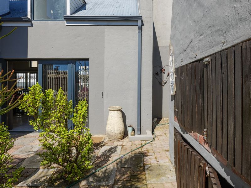 Rear courtyard area featuring a paved patio, built-in braai with timber shutters, and access to the main living space via a sliding door.