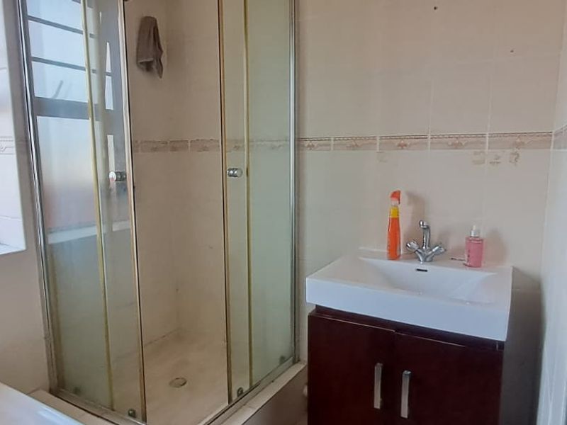 A functional bathroom featuring a shower enclosure, a vanity cabinet with a basin, and tiled walls.
