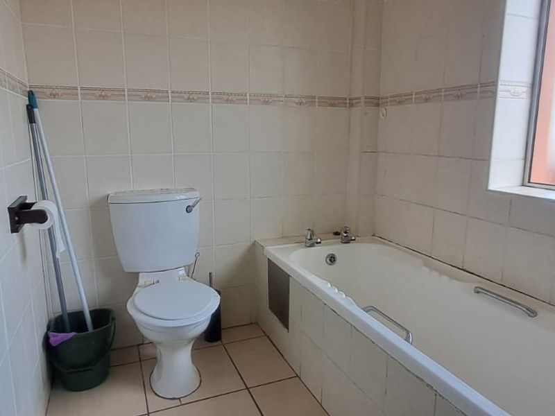 A dated bathroom featuring a standard bathtub, toilet, and tiled finishes, offering potential for modernization and renovation.