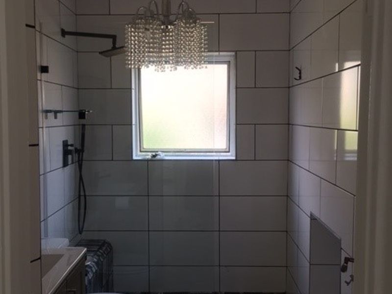 A modern bathroom featuring a walk-in shower with tiled walls, a vanity cabinet, and a toilet.