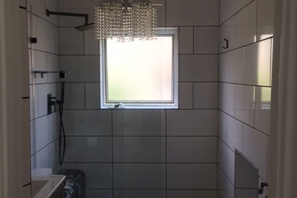A modern bathroom featuring a walk-in shower with tiled walls, a vanity cabinet, and a toilet.