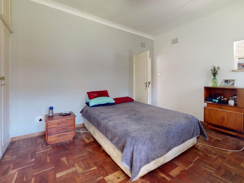 A bedroom featuring classic parquet flooring, built-in cupboards, and neutral wall finishes, offering a solid foundation for modern interior updates.