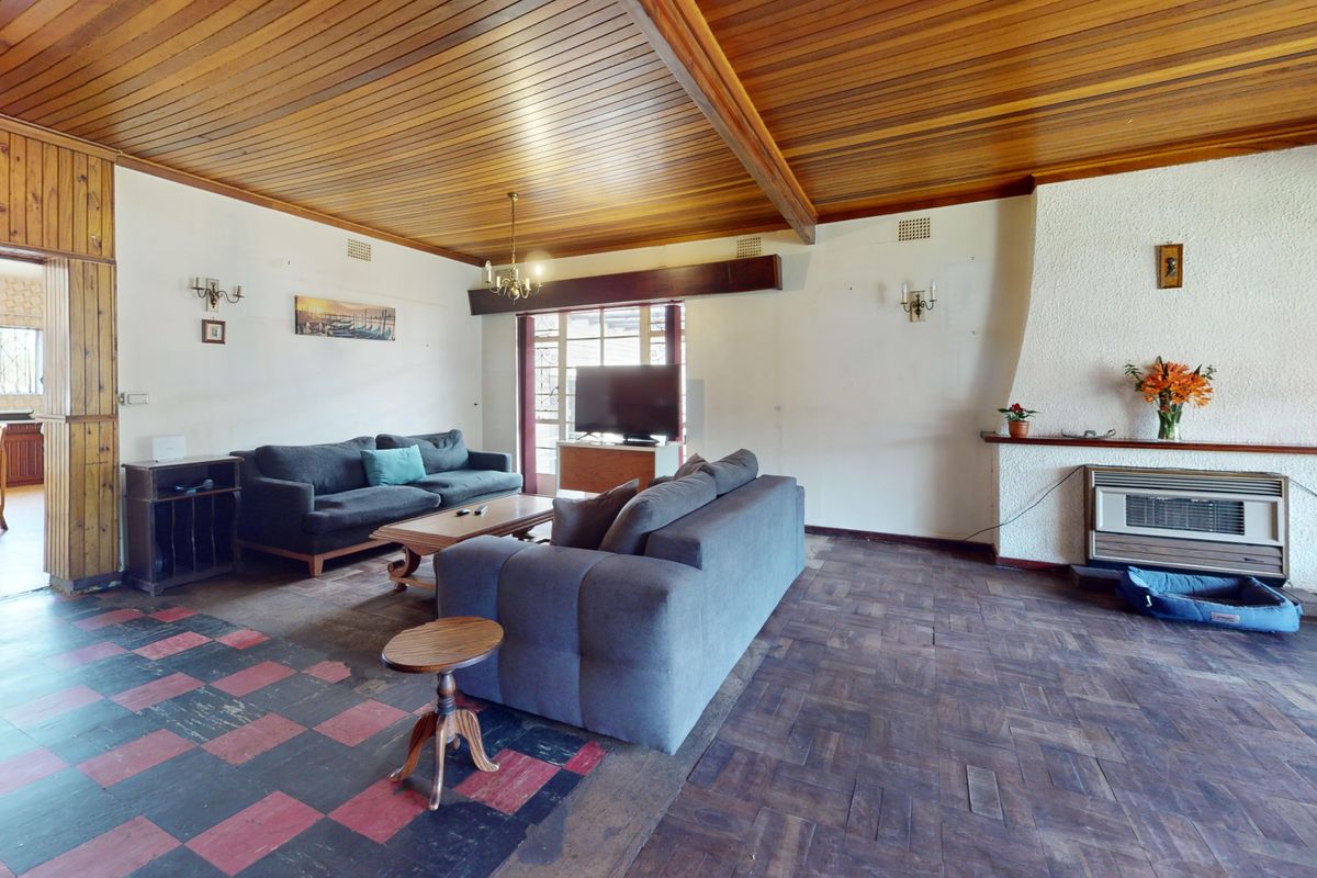 Spacious living room featuring a distinctive timber-clad ceiling, exposed beams, parquet flooring, and a textured fireplace surround with a built-in heater.
