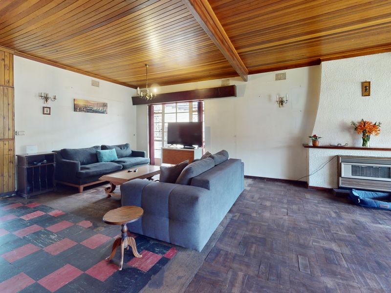 Spacious living room featuring a distinctive timber-clad ceiling, exposed beams, parquet flooring, and a textured fireplace surround with a built-in heater.