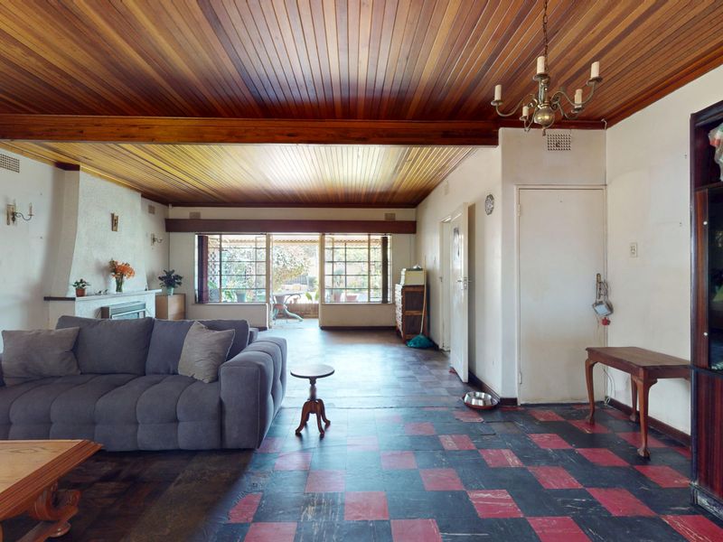 Spacious living room featuring a distinctive timber-clad ceiling, a fireplace, and direct access to the outdoor area through sliding glass doors.