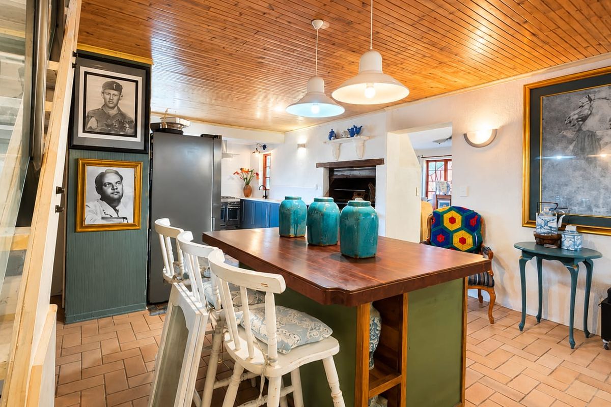 A rustic kitchen featuring a timber-clad ceiling, terracotta floor tiles, a central kitchen island, and a built-in fireplace, offering a warm and traditional aesthetic.