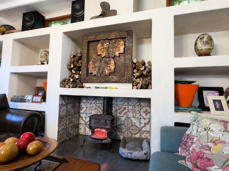 A cozy living room featuring a prominent built-in shelving unit and a cast iron fireplace with decorative tiled backing.