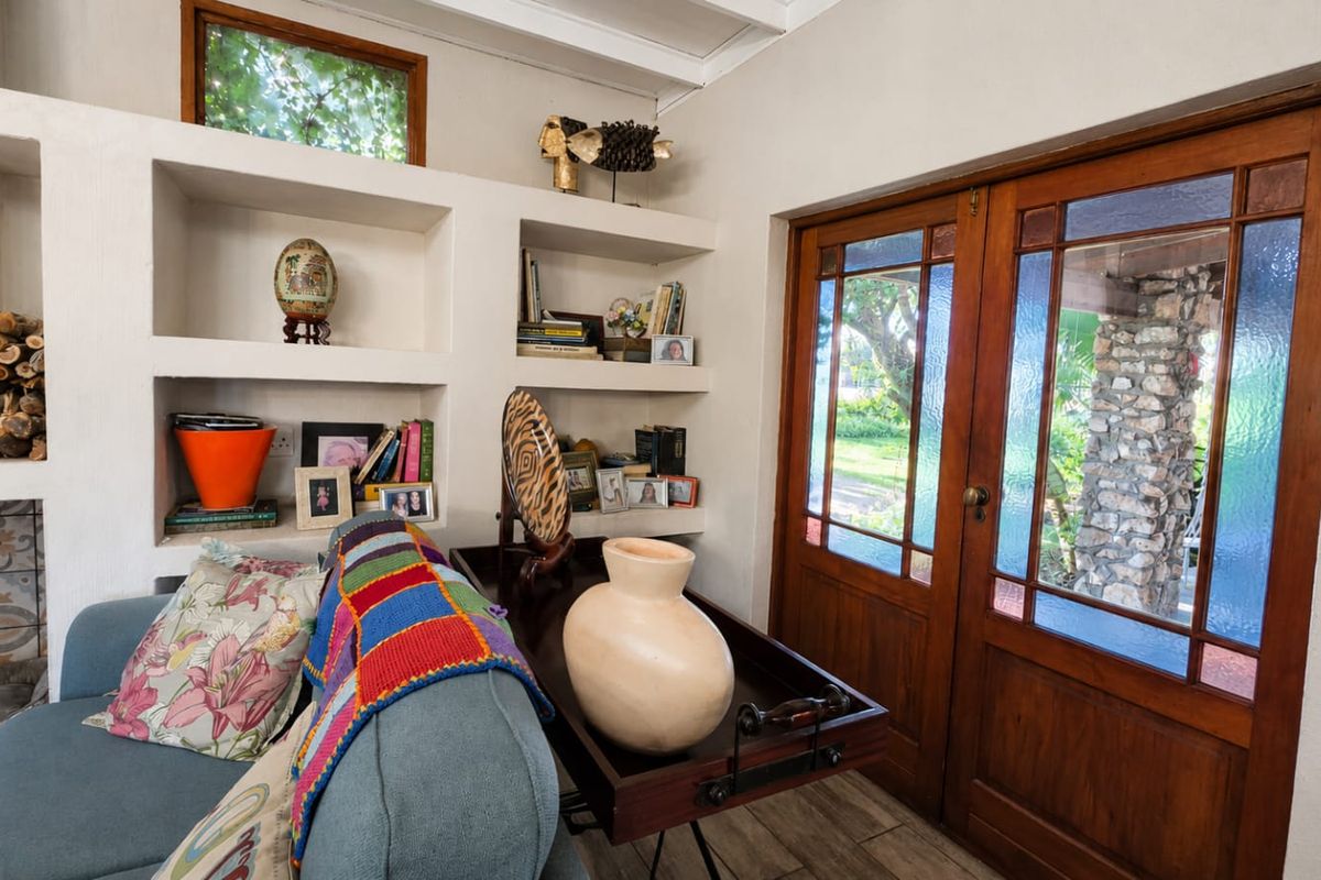 Cozy living area featuring built-in shelving, a fireplace with decorative tiling, and timber-framed glass doors providing access to the garden.
