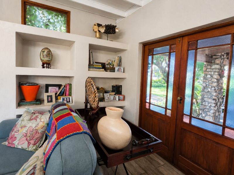 Cozy living area featuring built-in shelving, a fireplace with decorative tiling, and timber-framed glass doors providing access to the garden.