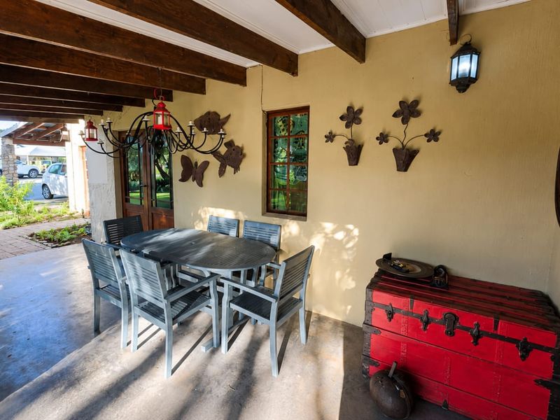 A covered patio area featuring exposed timber ceiling beams, a stone pillar, and concrete flooring, providing a pleasant outdoor entertainment space.