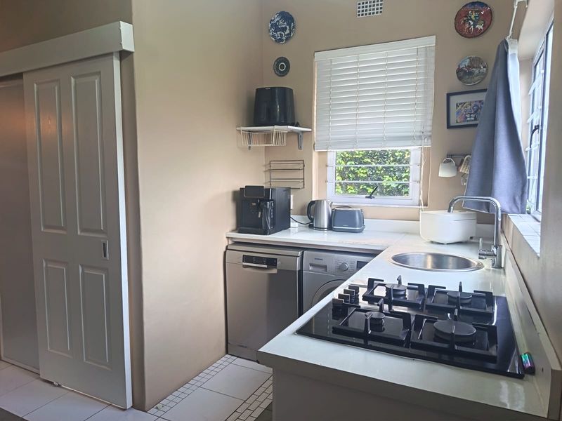 Compact kitchen featuring a gas hob, integrated sink, tiled flooring, and a sliding door, providing a functional workspace with natural light.