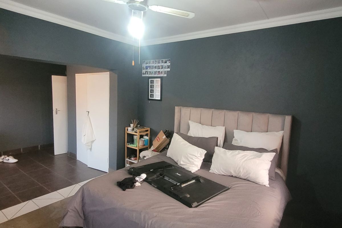 A bedroom featuring dark painted walls, tiled flooring, a ceiling fan, and a built-in cupboard.