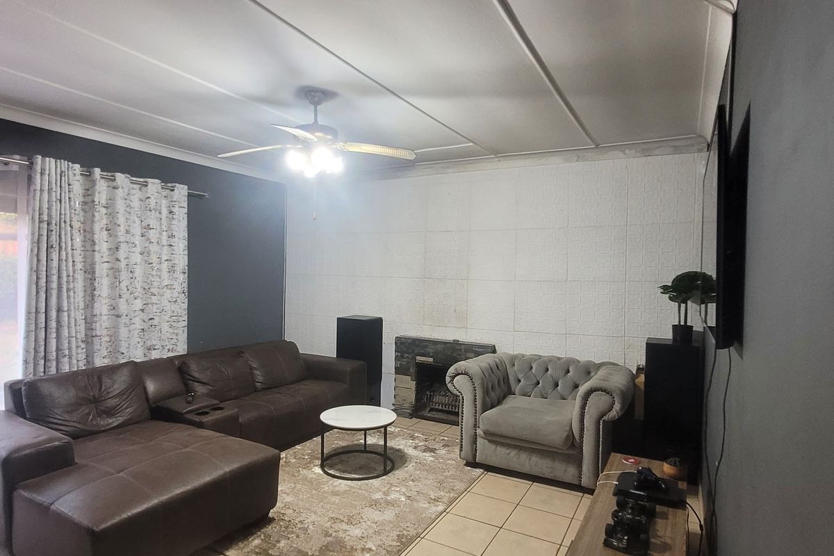 Living room featuring a fireplace, tiled flooring, and sliding glass door access to the exterior, with a ceiling fan and neutral wall finishes.