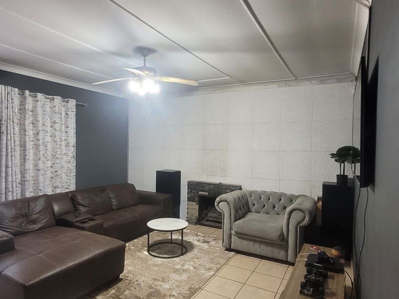 Living room featuring a fireplace, tiled flooring, and sliding glass door access to the exterior, with a ceiling fan and neutral wall finishes.