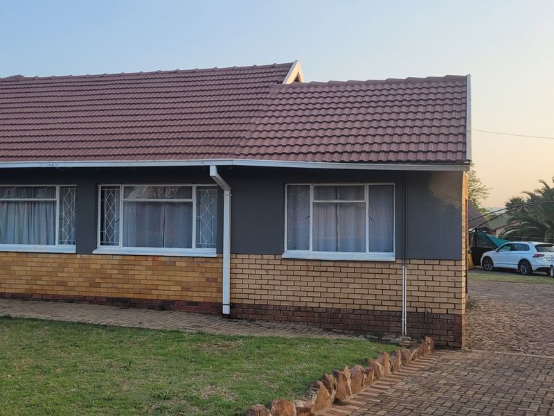 Front elevation of a single-story house featuring a tiled roof, brick and painted exterior walls, and a paved driveway.