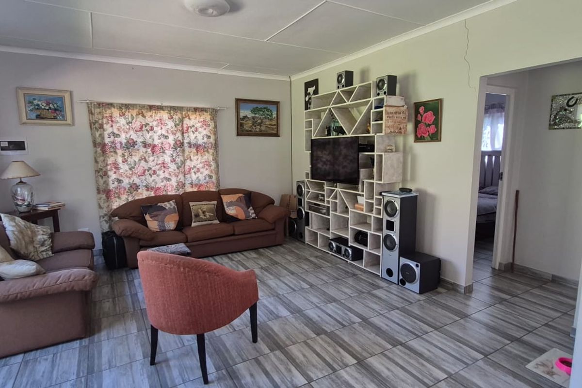 A living room featuring tiled flooring and a built-in shelving unit, with a visible wall crack requiring attention.