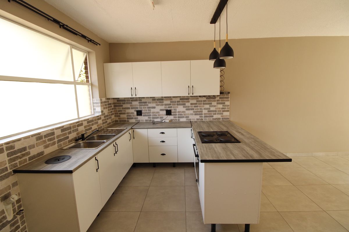 Modern kitchen featuring white cabinetry, wood-look laminate countertops, a built-in hob and oven, tiled backsplash, and neutral floor tiles.