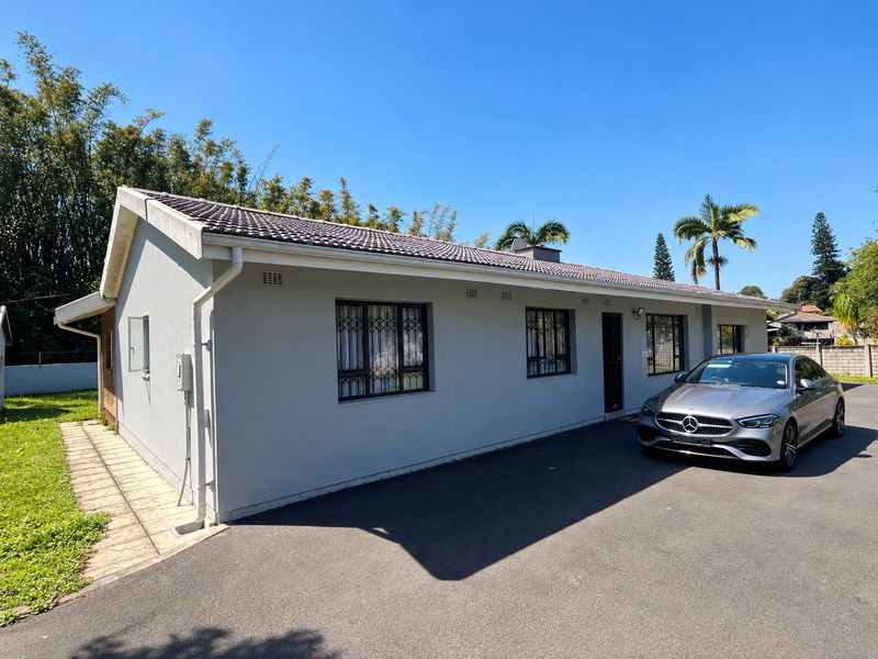 A well-maintained single-story residential property featuring a clean exterior facade, tiled roof, and a paved driveway area.